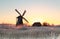 Sunrise over frosted meadow and windmill