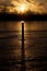 Sunrise over frozen lake with a pole in the ice casting long shadow