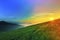 Sunrise over hills in mountains with green grass and blue sky wi
