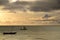 Sunrise over the Indian Ocean. Sailboat under yellow, cloudy sky