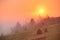 Sunrise over mountain field. Haystacks in misty autumn morning h