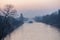 Sunrise over a waterway in Berlin at a misty morning with view to a freighter and a bridge in background.