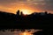 The sunrise peeking out from behind a mountain, with the silhouette of some high-rise buildings.