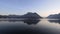 Sunrise on the placid waters of Lake Lugano with a view towards the town