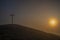 Sunrise on Radobyl hill with big cross and small statue in winter morning