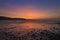 Sunrise reflected in the wet sand and pebbles of Freshwater East beach