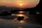 Sunrise reflected in the wet sand and rocks of Freshwater East beach