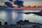 Sunrise on rocky shore and dramatic sky clouds