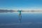 Sunrise on Salar de Uyuni in Bolivia covered with water, woman tourist on salt flat desert and sky reflections