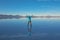 Sunrise on Salar de Uyuni in Bolivia covered with water, woman tourist on salt flat desert and sky reflections