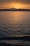 Sunrise on the Sardinian sea coast with intense orange color seen from the sea with five fishing boats on flat water