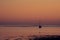 Sunrise scene by the ocean with warm orange color. Silhouette of a small yachts sailing. Calm and peaceful scene