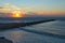 Sunrise on the sea with a breakwater made of rocks entering in the sea