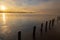 A sunrise seen from the shore of a lake during winter time. The rising sun reflects in the thin layer of ice on the water between