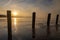 A sunrise seen from the shore of a lake during winter time. The rising sun reflects in the thin layer of ice on the water between