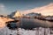 Sunrise on snowy mountain with scandinavian village at coastline in winter