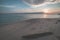 Sunrise on tropical beach, wide angle view in backlight from the coral sandy beach with tree trunk, toned image.