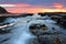 Sunrise waves flowing into rock chasm seascape