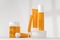 Sunscreen bottles on podium 3d render. Skincare lotion, beauty cosmetic cream, mockup of blank orange tubes and jars
