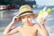 Sunscreen is on the caucasian kidâ€™s face. Child is holding containers of the suntan lotion. Sun protection. Summer holiday,