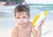 Sunscreen is on the caucasian kidâ€™s face. Child is holding containers of the suntan lotion. Sun protection. Summer holiday.