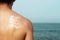 Sunscreen on a man`s back against the sea, skin protection concept