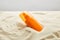 Sunscreen in orange bottle in sand