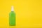 Sunscreen spray against yellow background with copy space. Sunscreen product for tanning in green plastic tube.