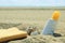 Sunscreen tube on the sand next to the beach. Empty copy space