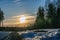 Sunset above Swedish pine tree forest, curvy road asphalt road turns right. Dirty spring snow at forest side. Northern Sweden