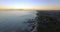 Sunset, aerial city and coast with sea, beach and town with drone view and skyline. Water, cityscape and ocean with