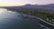 Sunset, aerial and coast mountain with sea, beach and town with drone view and skyline. Water, cityscape and ocean with