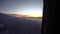 Sunset from the airplane window. View of the orange sun, aircraft wing, dark sky and clouds.