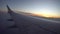 Sunset from the airplane window. View of the orange sun, aircraft wing, dark sky and clouds.