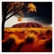 Sunset in the arid Australian desert with red dirt and large rock formation