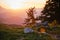 Sunset in the Austrian Alps with shades of orange, out of focus mountain layers, and a stone near a hiking trail in the foreground