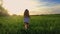 Sunset back shot of cute teenager girl wears dress runing on green meadow. 120 fps, slowmotion.