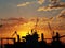 Sunset on a background of silhouettes from ship cranes arriving at the port