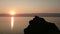 Sunset on the Baikal. On the rock sits a bird. Silhouette of birds and rocks. Evening. Sunset. Horizon. Summer.