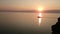 Sunset on the Baikal. On the rock sits a bird. Silhouette of birds and rocks. Evening. Sunset. Horizon. Summer.