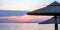 Sunset on the beach. Greece. Straw umbrella, reflection on rippled ocean water