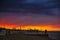 A sunset in a beach with a refinery in the background