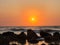 Sunset at a beach with rocks on the shore.