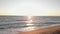 Sunset on beach. Sea waves crashing and splashing on sand beach. Red sunset over sea, sun touches horizon. Summer sunset seascape,