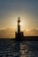 Sunset behind an ancient stone lighthouse Veneitian Port, Chania, Crete