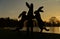 Sunset behind silhouetted dancing hares sculpture. Wisley.