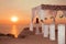 Sunset. bride silhouette. Wedding ceremony arch with flower arrangement and white curtain on cliff above sea, outdoor photo.