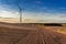 Sunset at brown field, blue sky and wind turbine, Poland