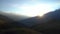 Sunset in the Caucasian mountains. The sun sets behind high mountains covered with clouds and fog.