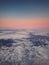 Sunset cloudscape, aerial view out of the plane window above the fluffy clouds. Tranquil sky evening scene, misty nebula. Air